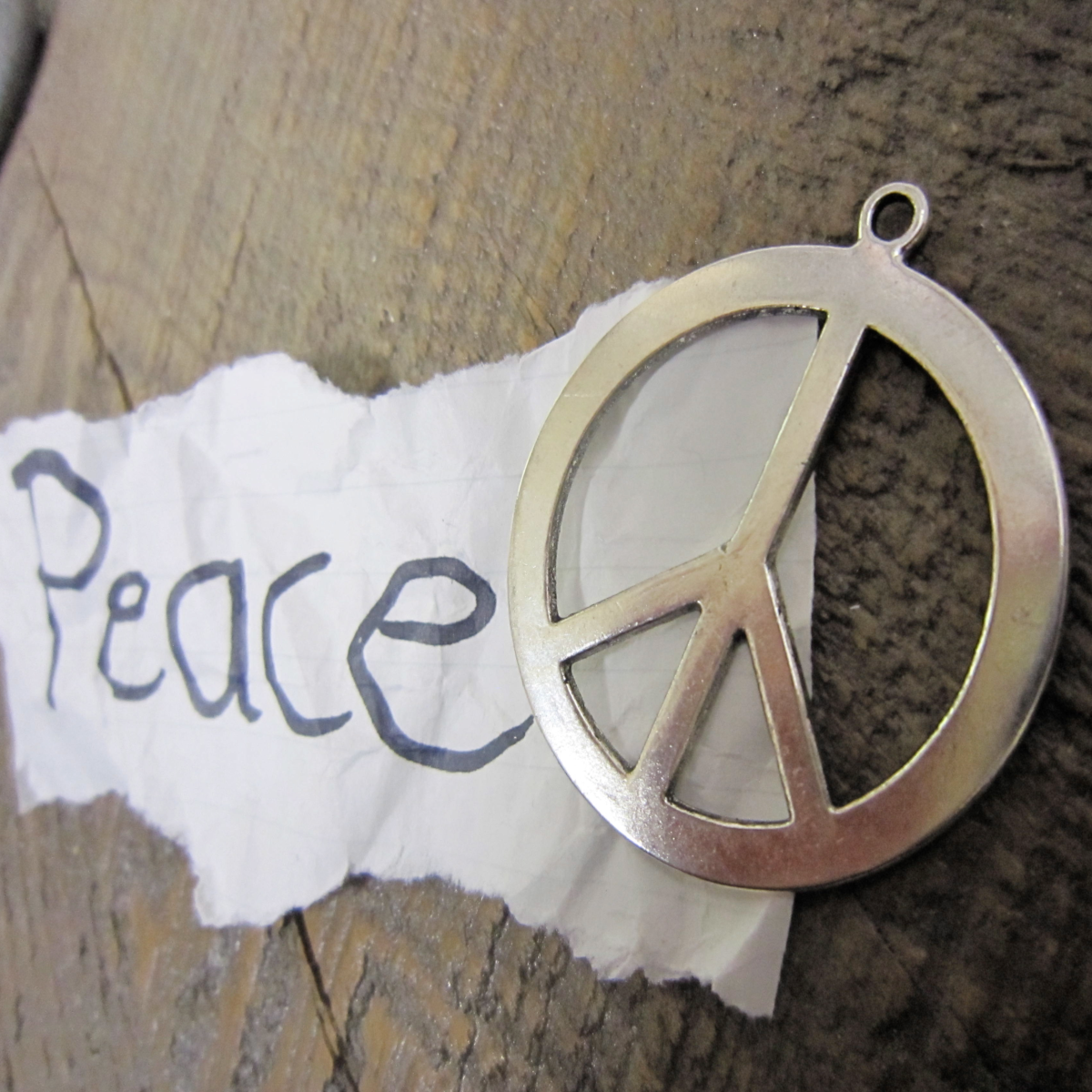 photo of peace symbol and torn sheet of paper with word peace on it
